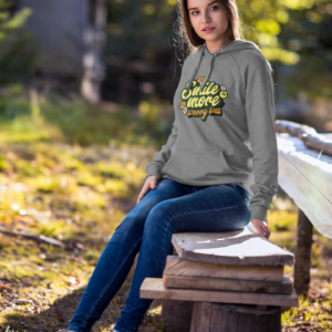 Woman wearing a hoodie with text sitting on a wooden bench outdoors.